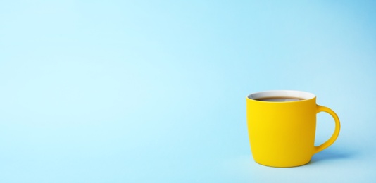 Yellow ceramic cup with hot aromatic coffee on color background