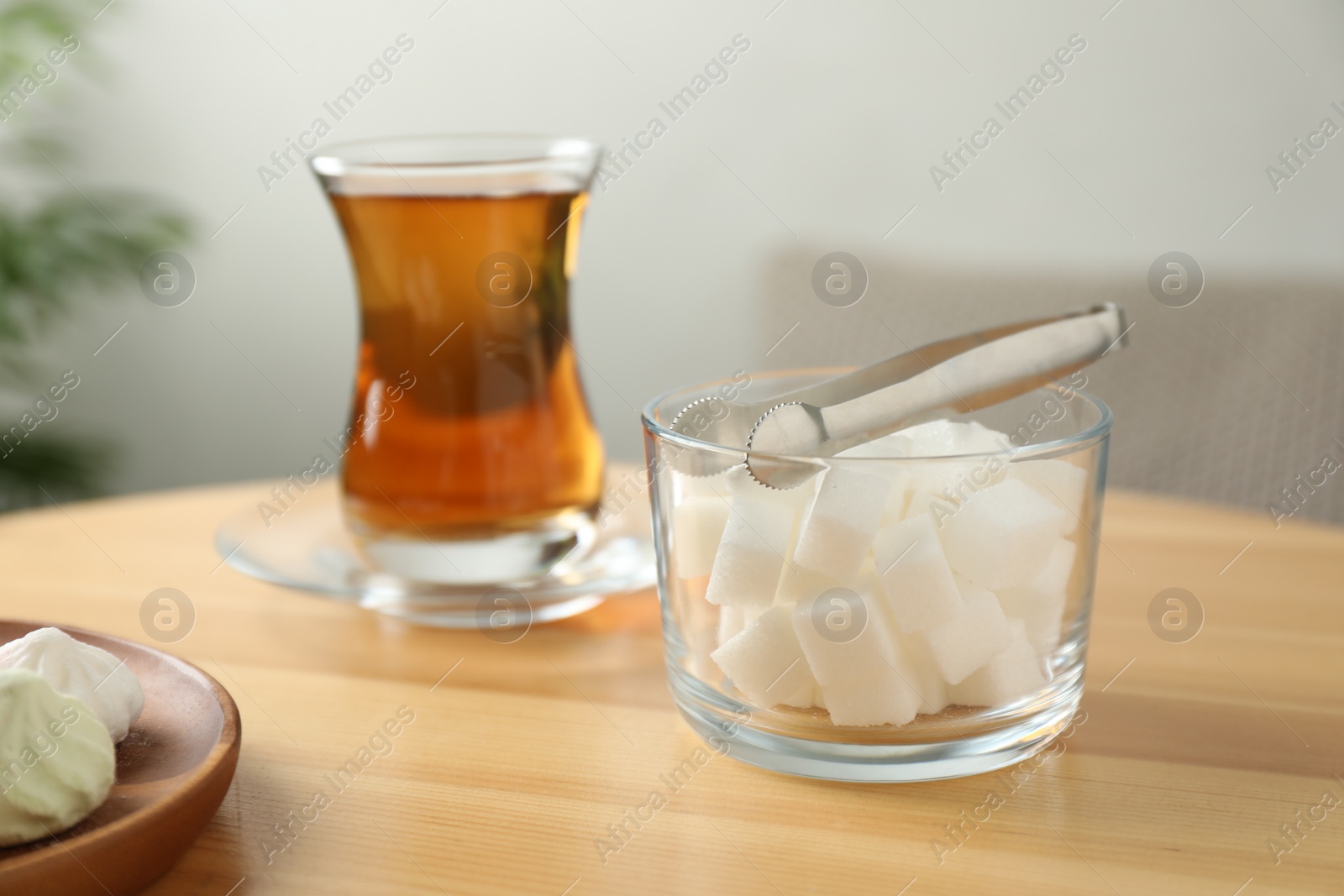 Photo of Sugar cubes and aromatic tea in glass on wooden table