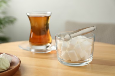 Photo of Sugar cubes and aromatic tea in glass on wooden table