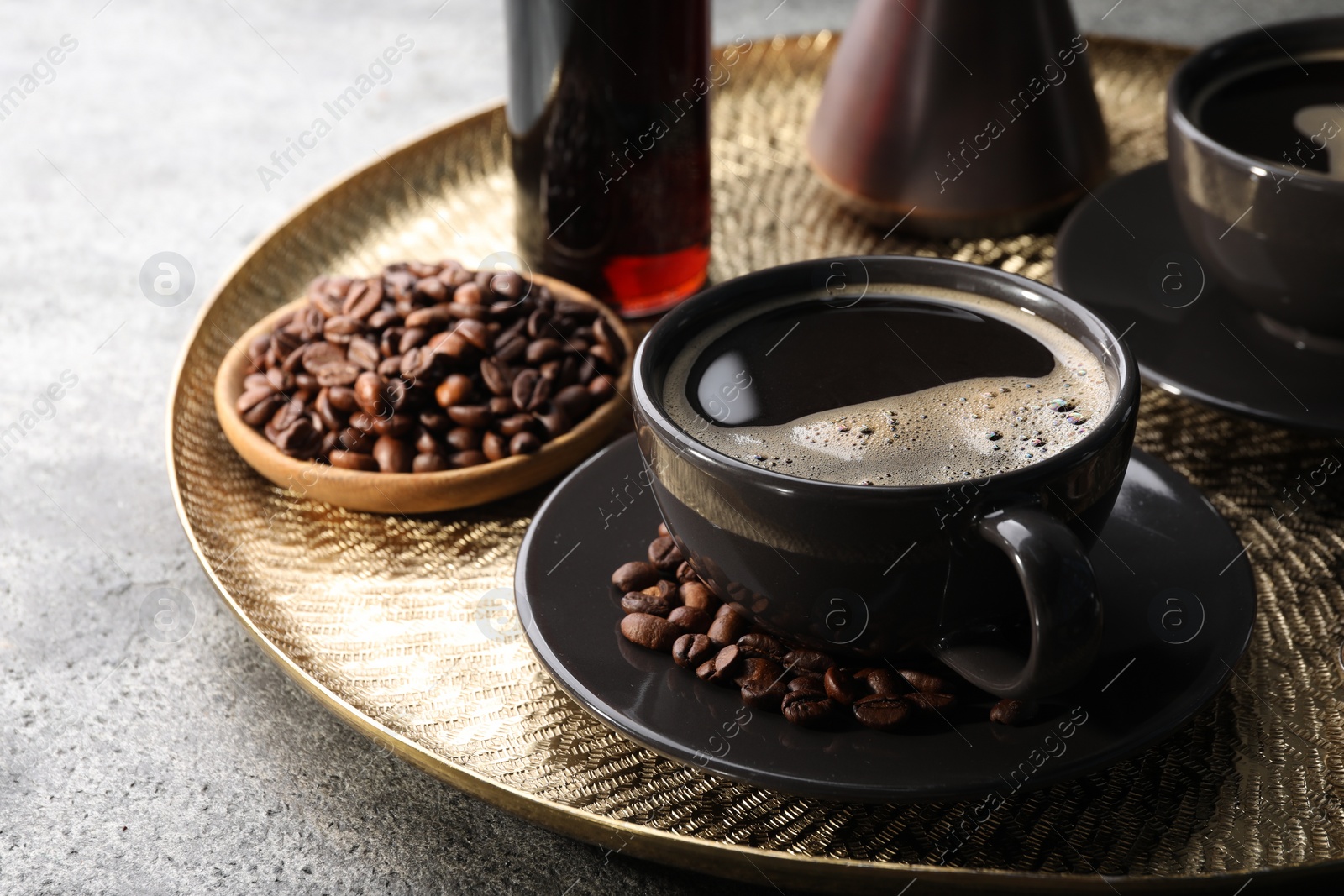 Photo of Delicious syrup, cup of coffee and beans on grey table