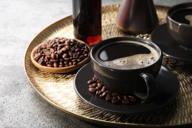 Delicious syrup, cup of coffee and beans on grey table