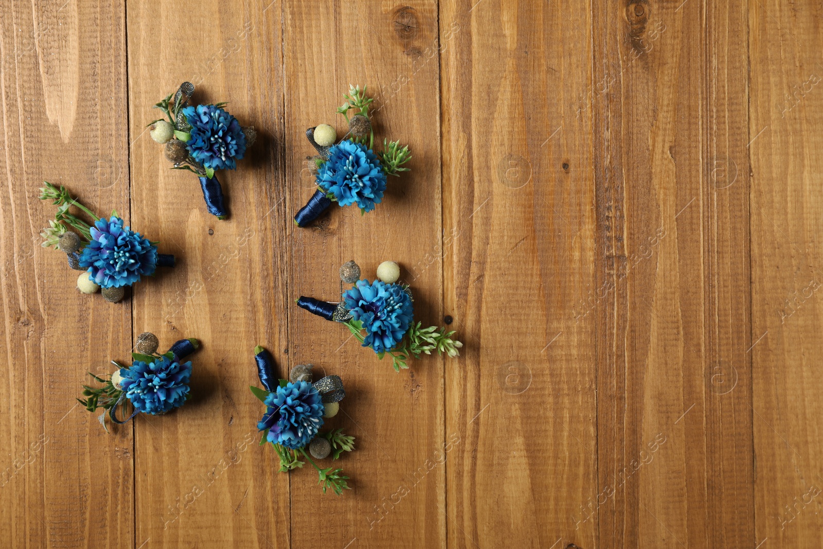 Photo of Stylish blue boutonnieres on wooden table, flat lay. Space for text