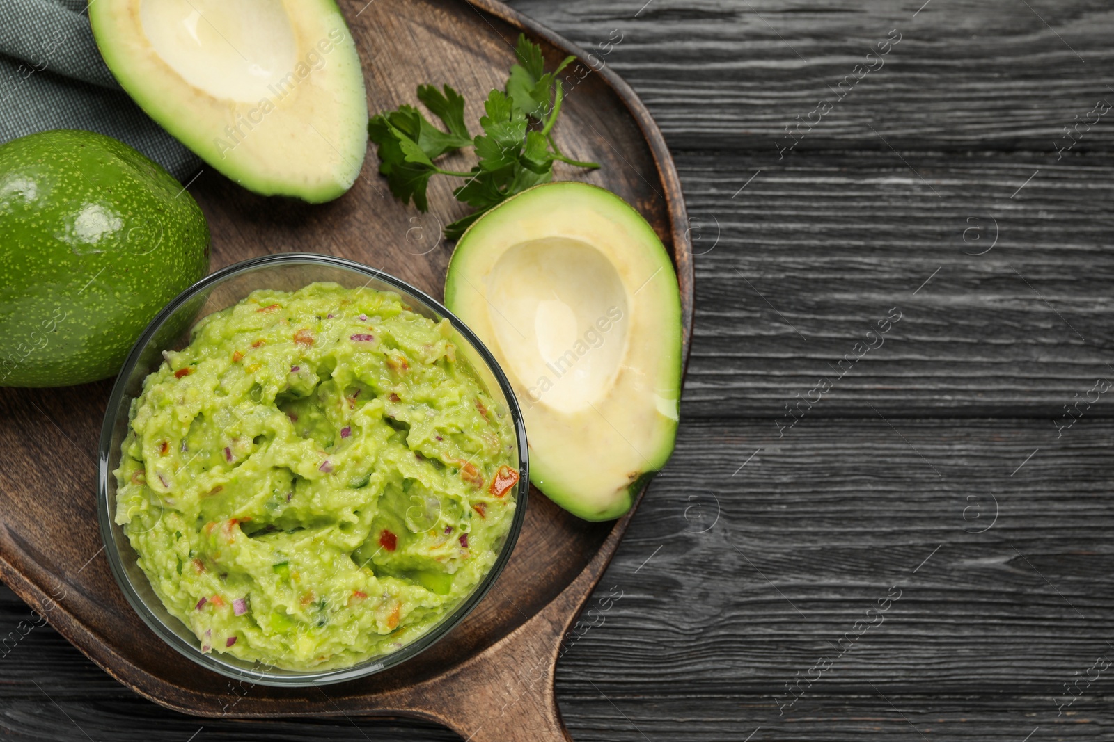 Photo of Delicious guacamole with parsley and fresh avocado on wooden table, flat lay. Space for text