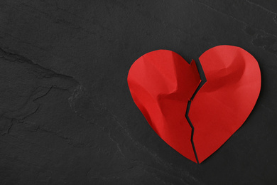 Photo of Torn paper heart on black stone background, top view with space for text. Relationship problems concept