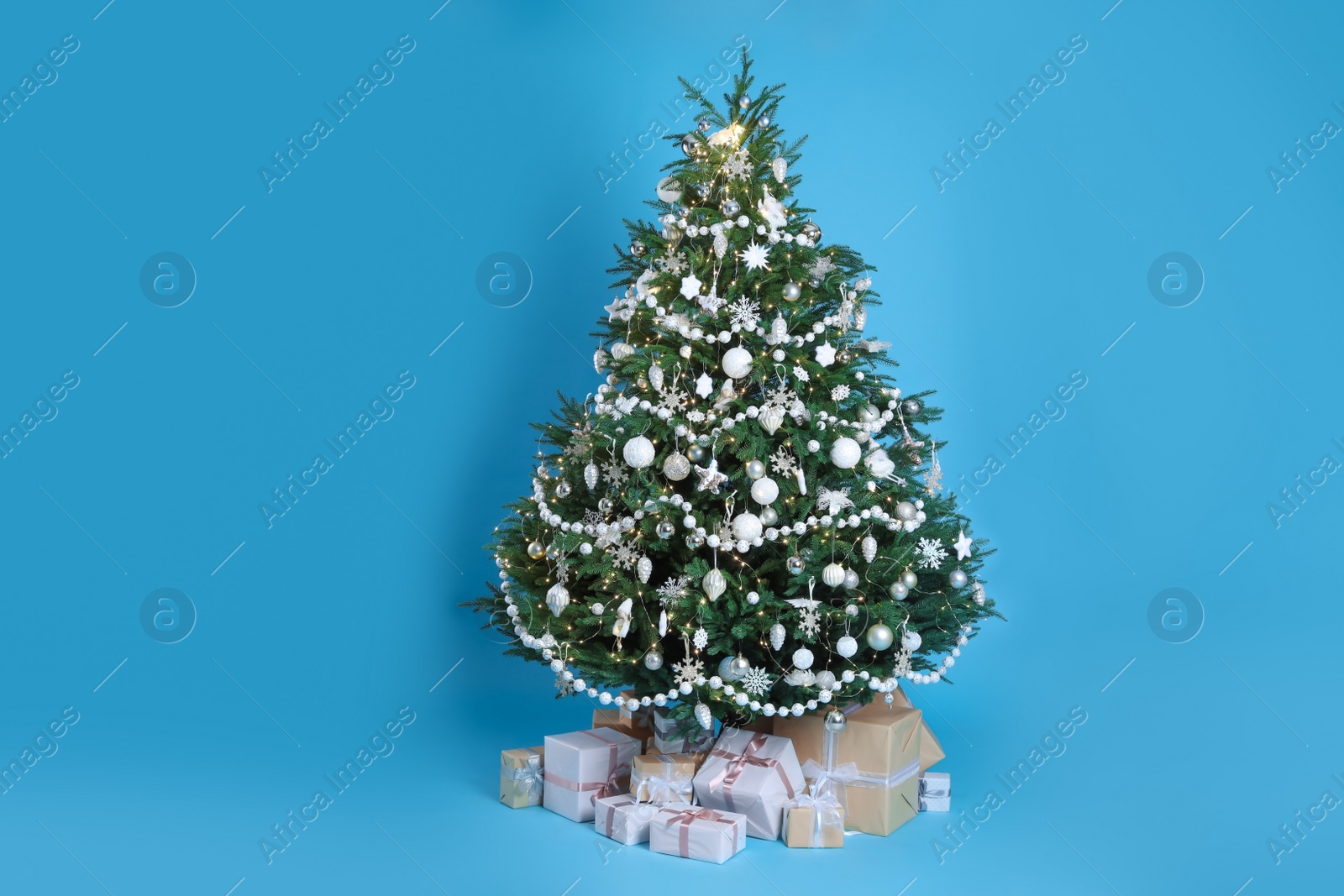 Photo of Beautiful Christmas tree and gift boxes on light blue background