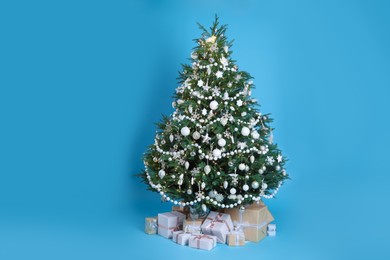 Photo of Beautiful Christmas tree and gift boxes on light blue background