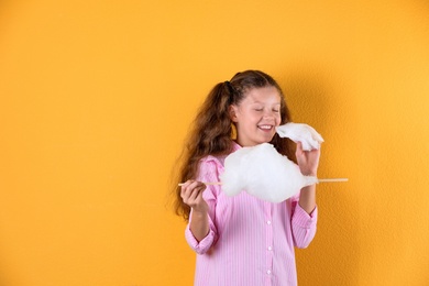 Photo of Little girl with cotton candy on color background