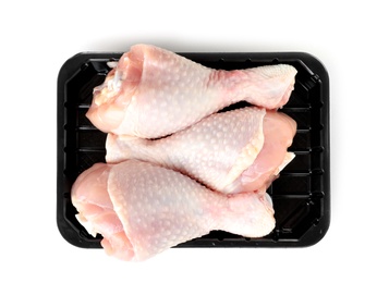 Photo of Plastic container with raw chicken drumsticks on white background, top view. Fresh meat