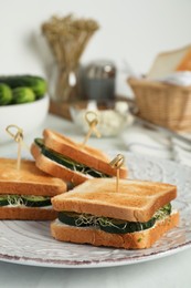 Photo of Tasty sandwiches with cucumber, cream cheese and microgreens on white table, closeup