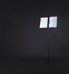 Photo of Note stand with music sheets on black background. Space for text