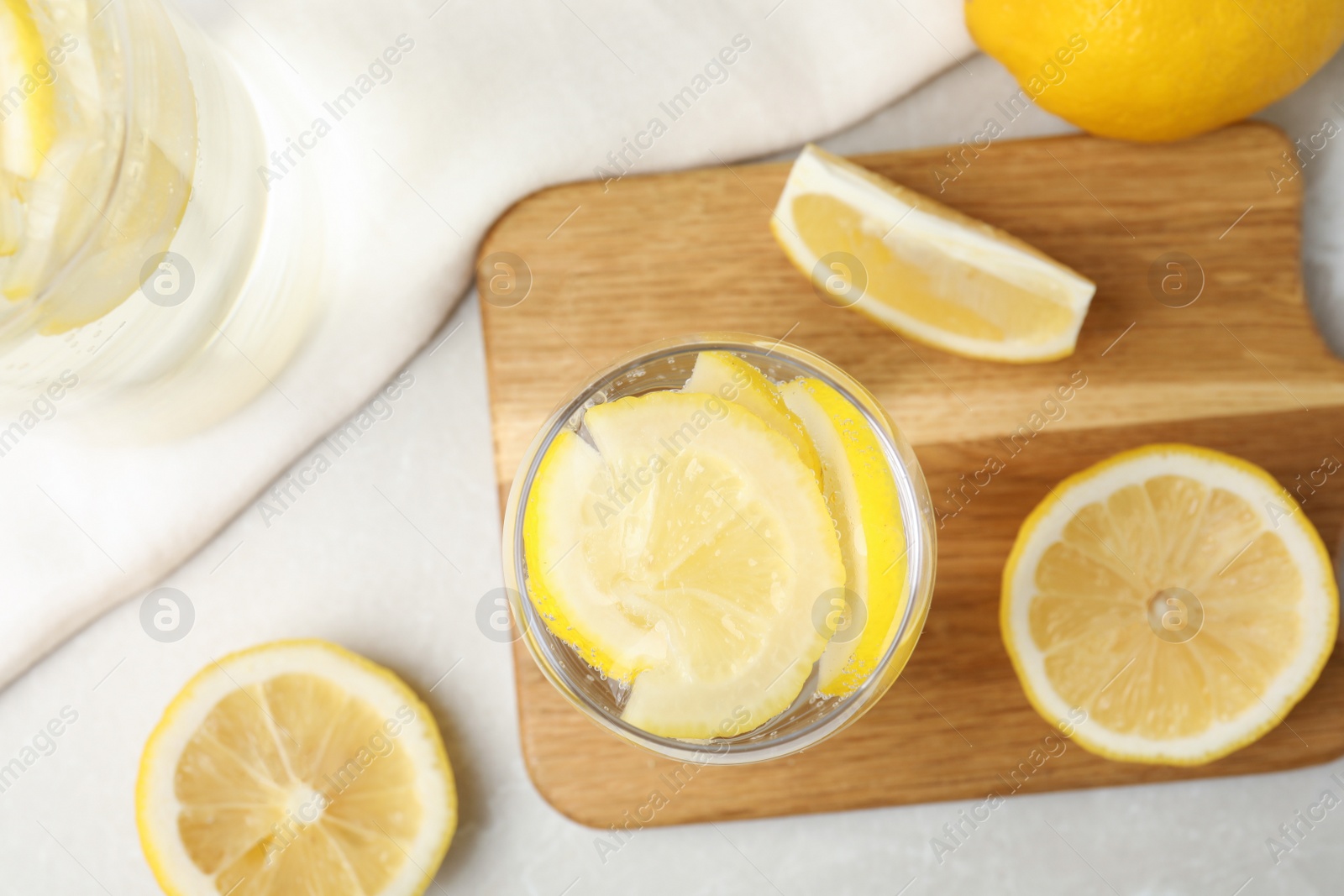 Photo of Soda water with lemon slices on light table, flat lay