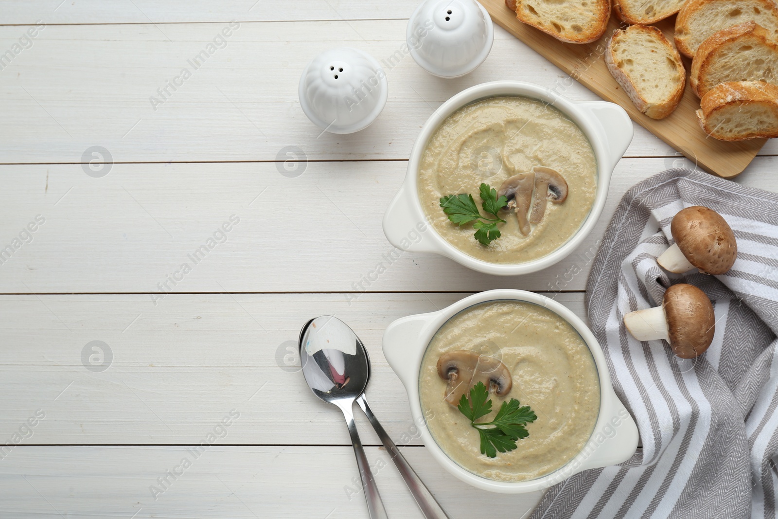 Photo of Delicious mushroom cream soup with parsley served on white wooden table, flat lay. Space for text