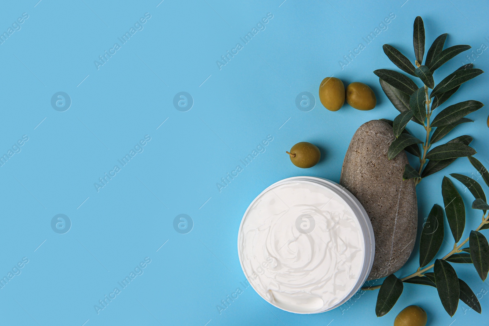 Photo of Flat lay composition with jar of cream and olives on light blue background. Space for text