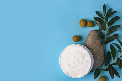 Flat lay composition with jar of cream and olives on light blue background. Space for text