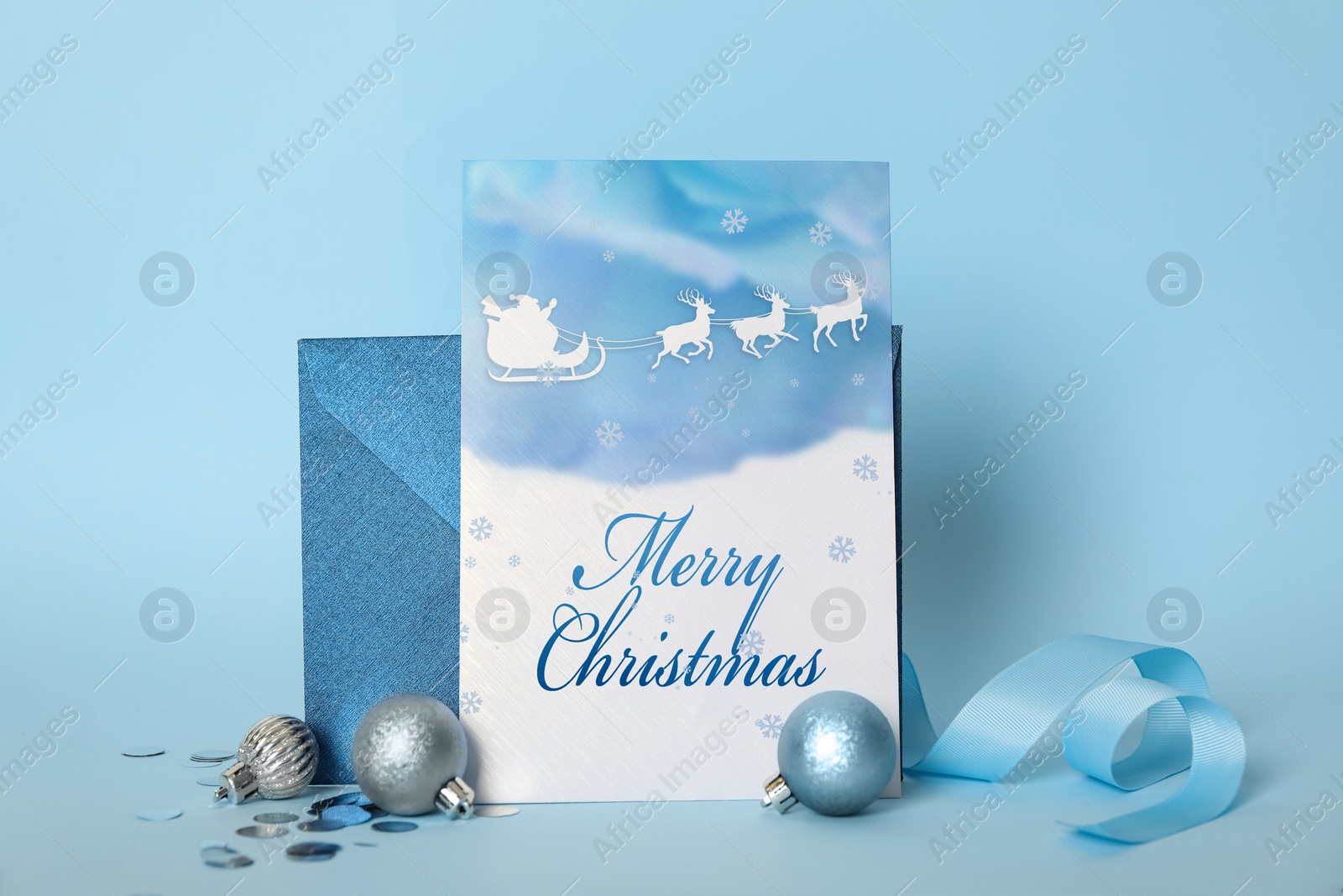 Image of Greeting card with text Merry Christmas, envelope and balls on light blue background