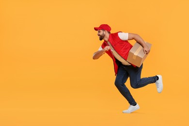 Photo of Smiling courier running to deliver parcel on orange background, space for text