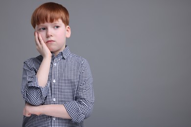 Photo of Portrait of sad little boy on grey background, space for text