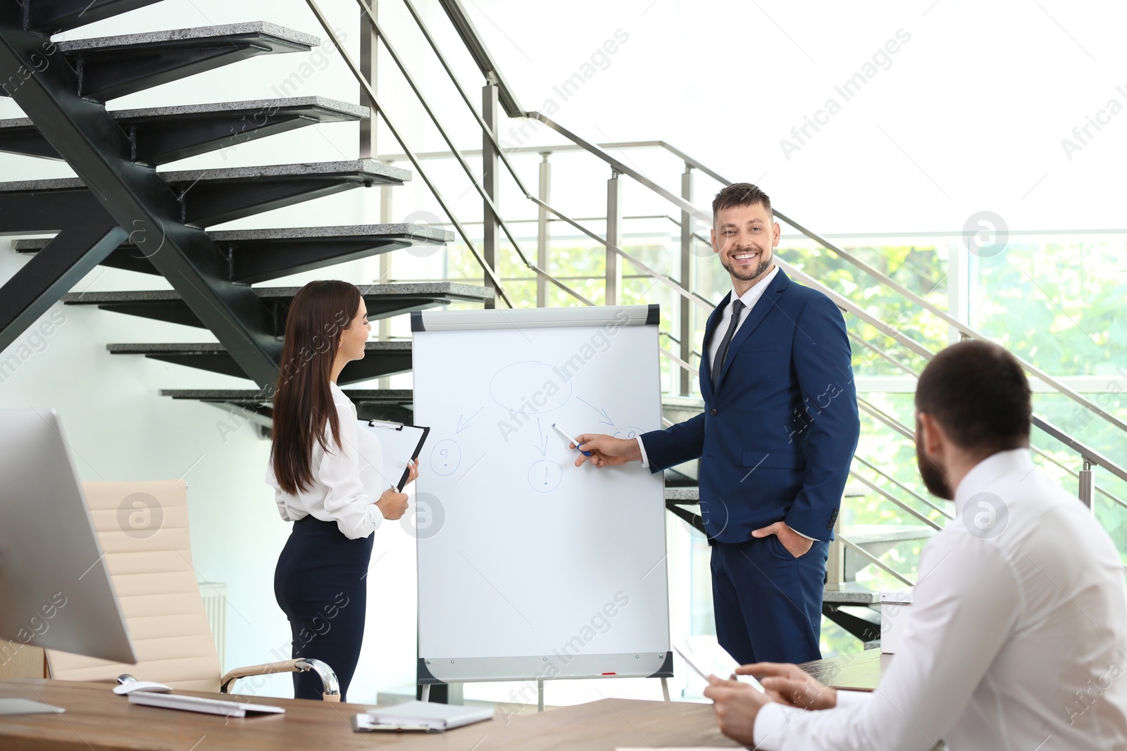 Photo of Man helping his colleague to give presentation on meeting in office