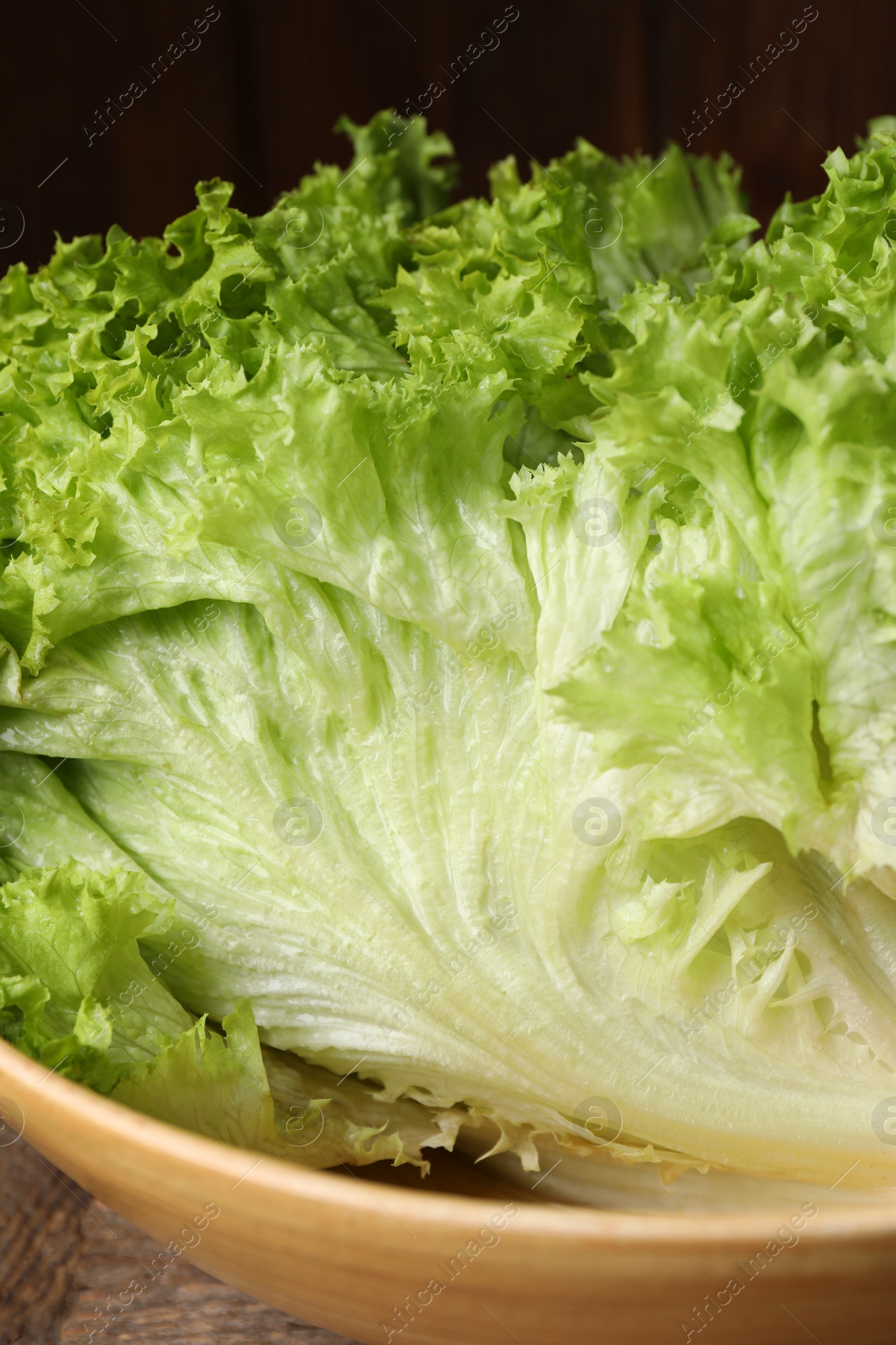 Photo of Fresh lettuce on wooden table, closeup. Salad greens