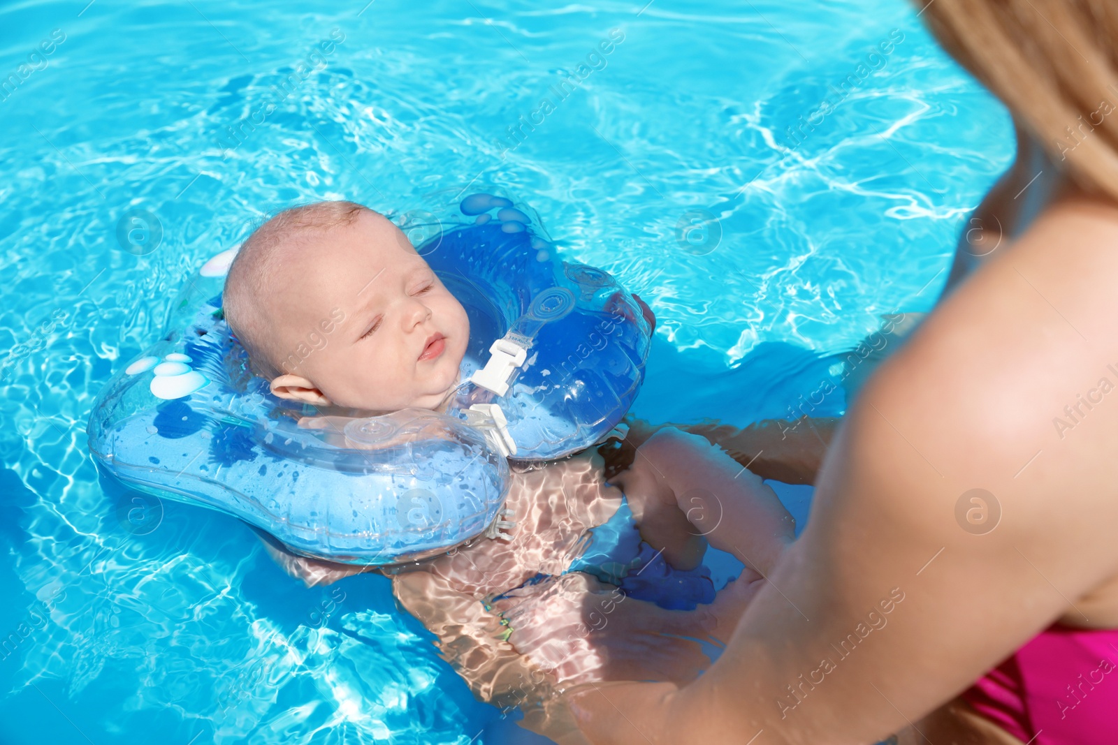 Photo of Woman with her little baby in swimming pool on sunny day, outdoors