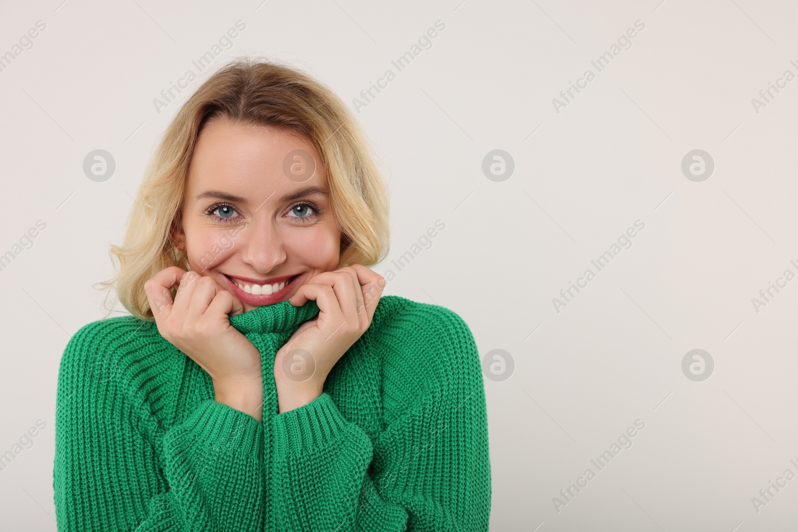 Photo of Happy woman in stylish warm sweater on white background. Space for text