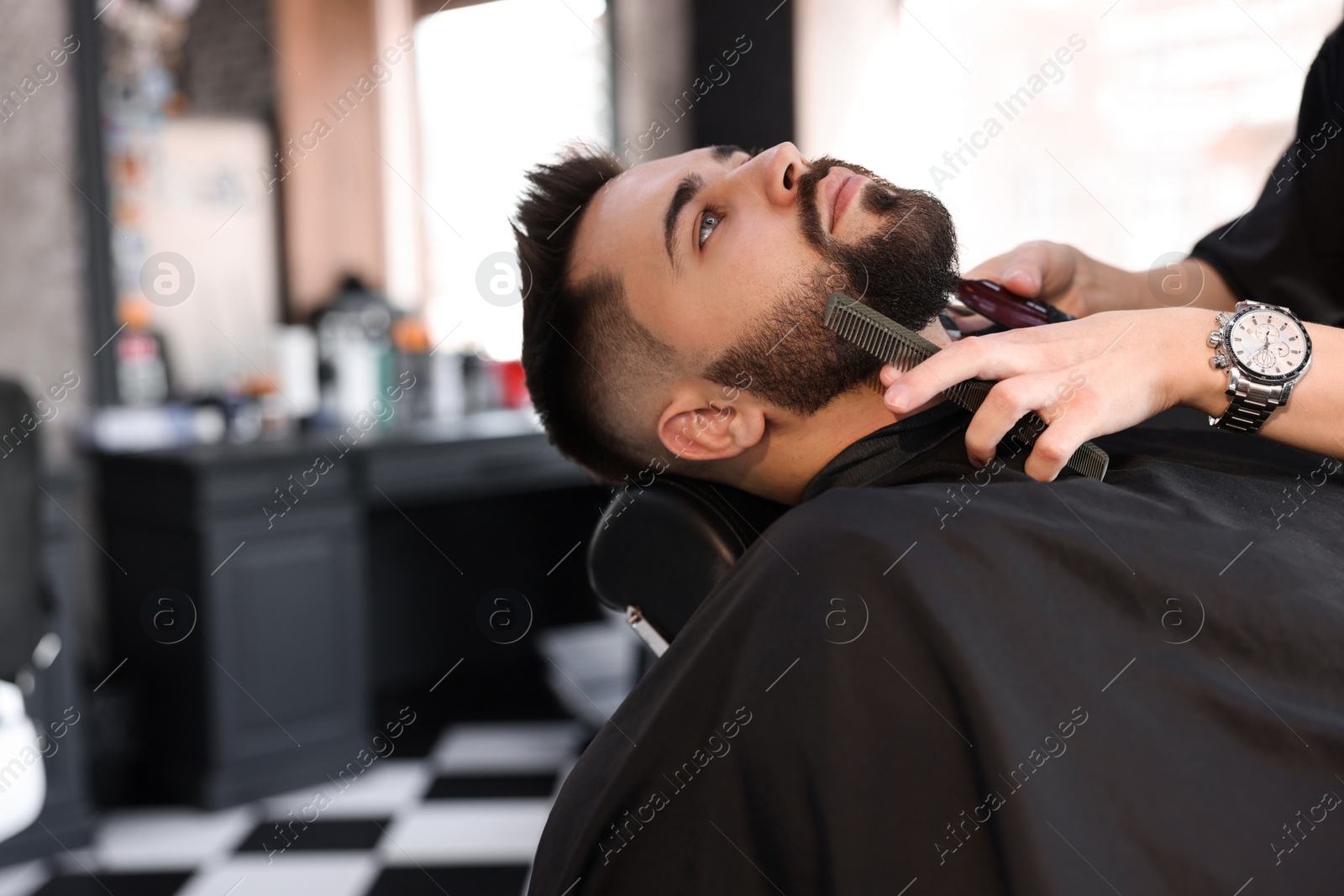 Photo of Professional hairdresser working with client in barbershop