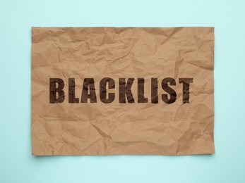 Image of Crumpled paper with word Blacklist on light blue background, top view