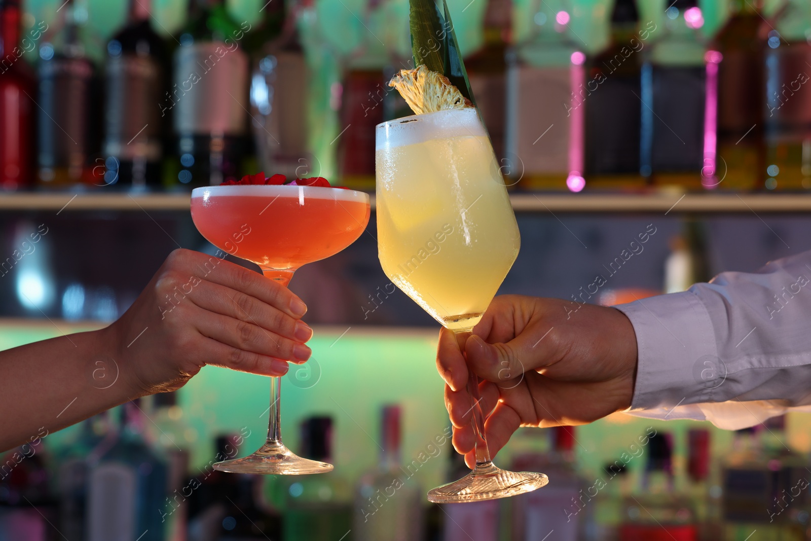 Photo of Man and woman clinking glasses with alcoholic cocktails in bar, closeup