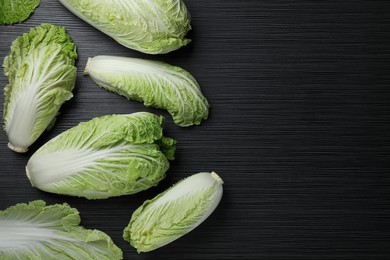 Photo of Fresh ripe Chinese cabbages on black wooden table, fat lay. Space for text