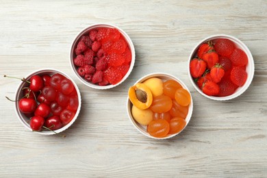Delicious gummy candies and fresh fruits on white wooden table, flat lay