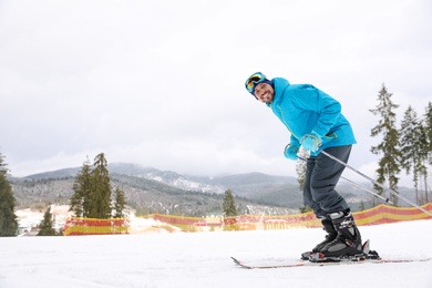 Male skier on slope at resort, space for text. Winter vacation