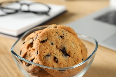 Chocolate chip cookies on wooden table at workplace, closeup