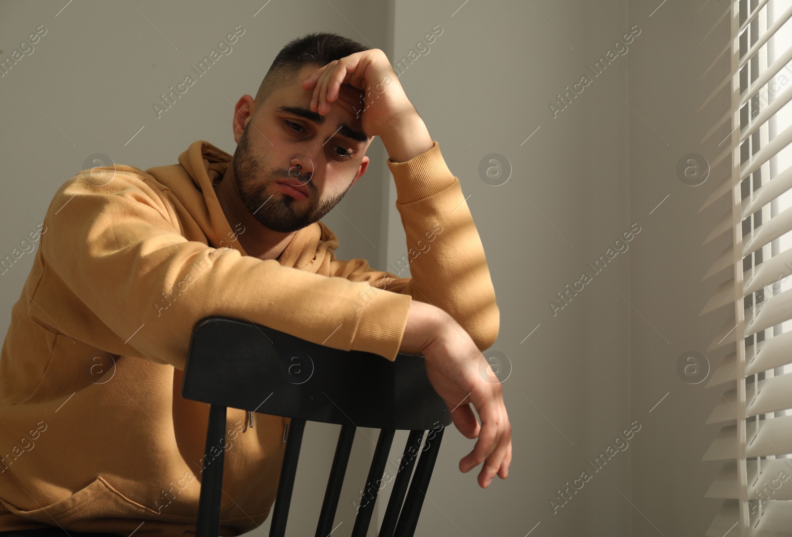 Photo of Sad man sitting on chair near window. Space for text