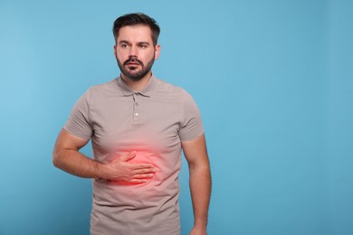 Image of Man suffering from stomach pain on light blue background, space for text