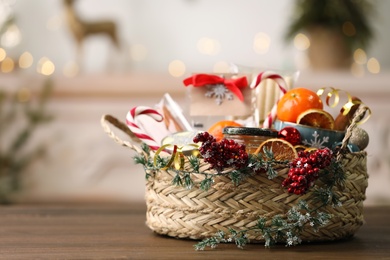 Photo of Wicker basket with Christmas gift set on wooden table. Space for text