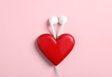 Photo of Modern earphones and red heart on pink background, flat lay. Listening love music songs