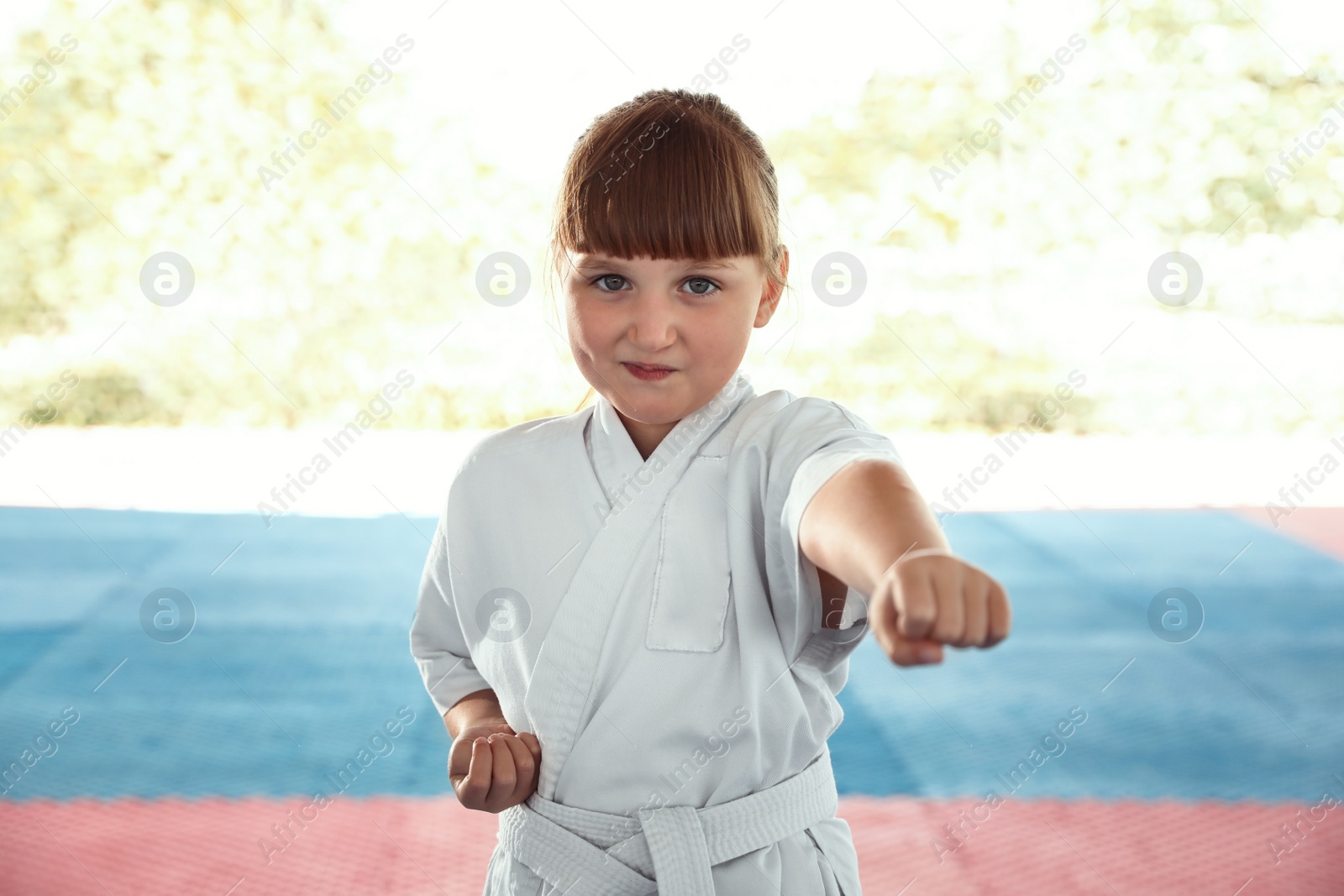 Photo of Girl in kimono practicing karate on tatami outdoors