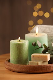 Spa composition. Burning candles, soap, towel and eucalyptus branch on wooden table