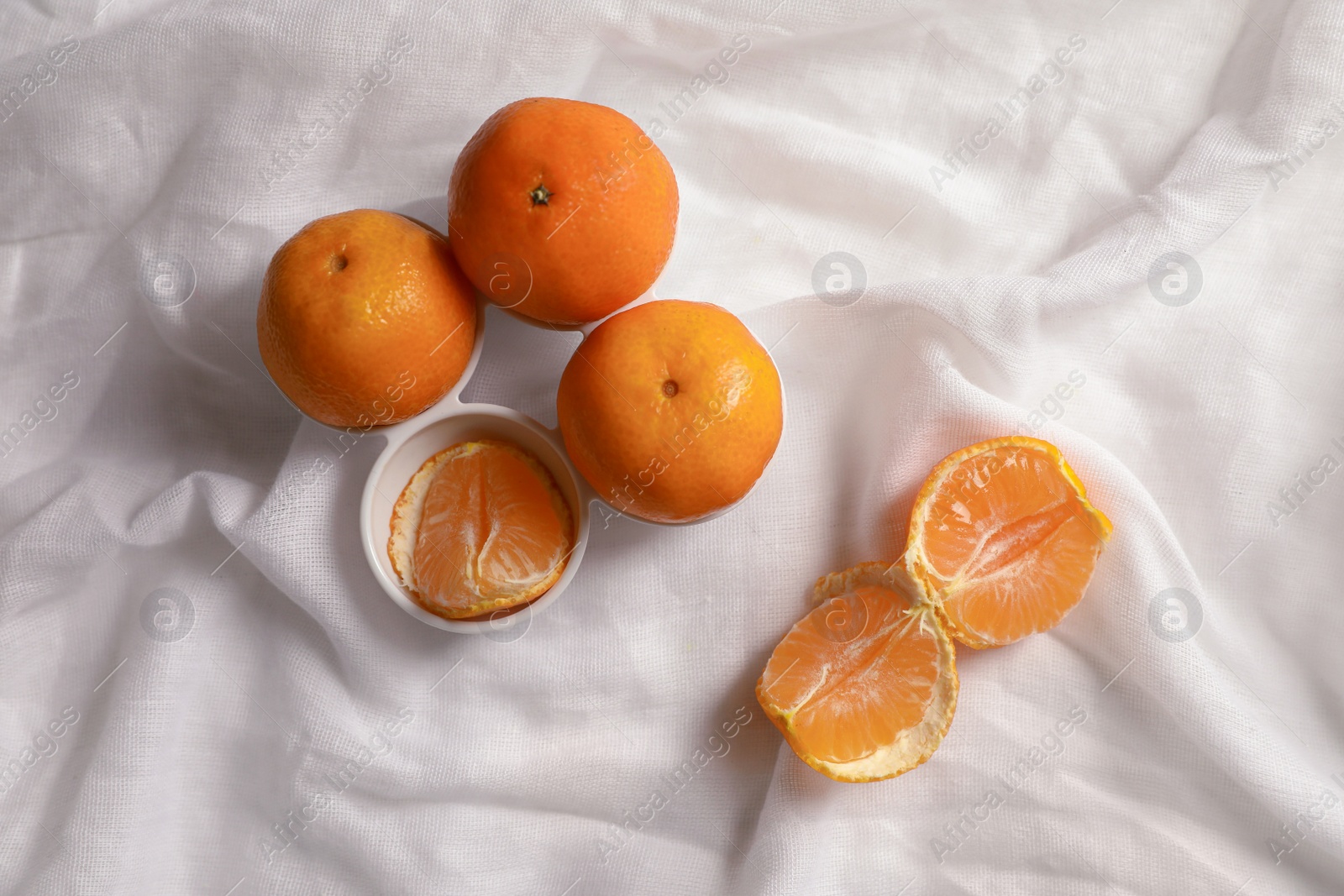 Photo of Fresh ripe tangerines on white cloth, flat lay