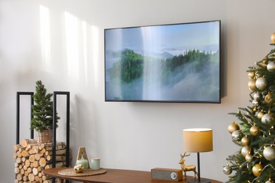Photo of Modern TV set on light wall in room decorated for Christmas