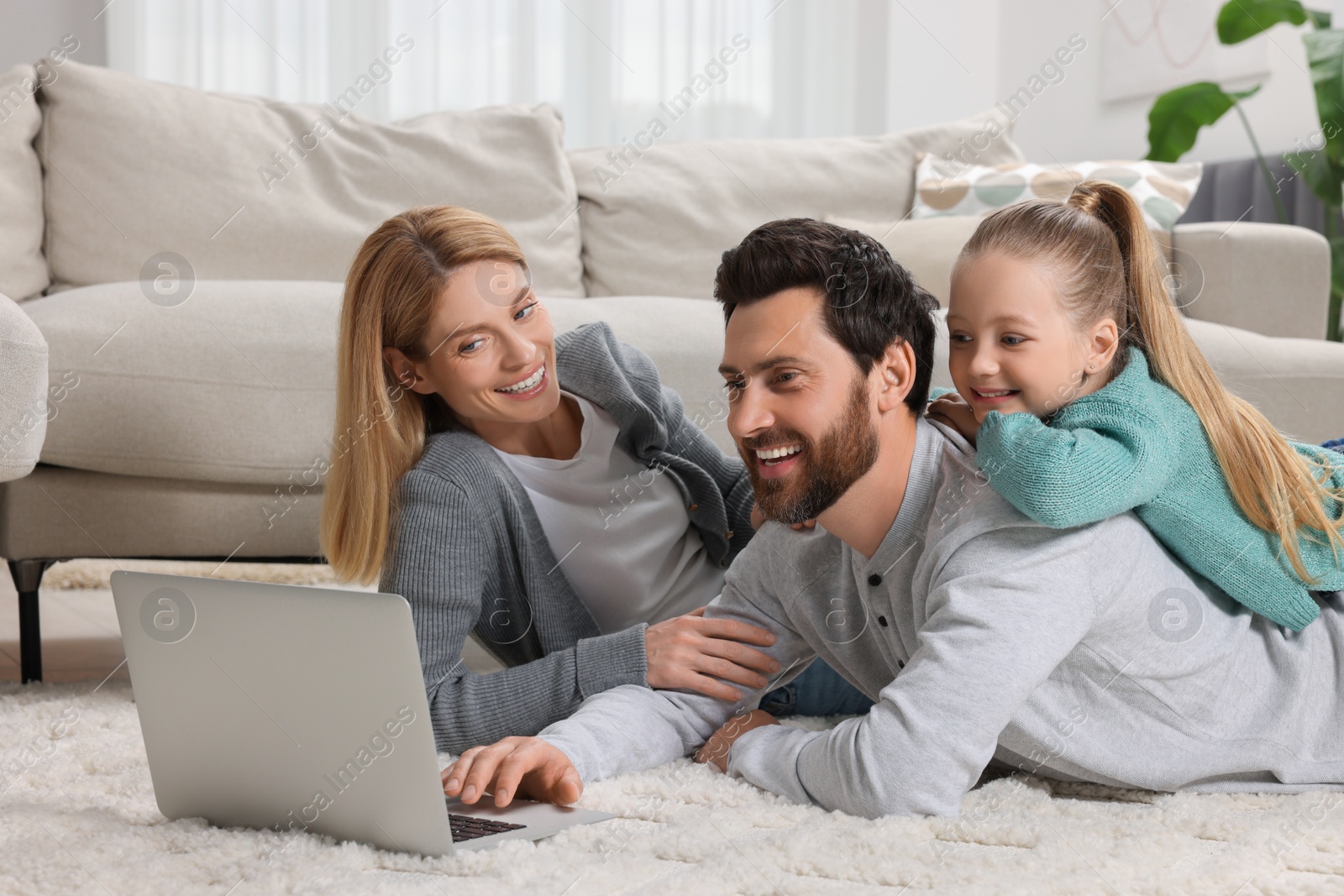 Photo of Happy family with laptop on floor at home