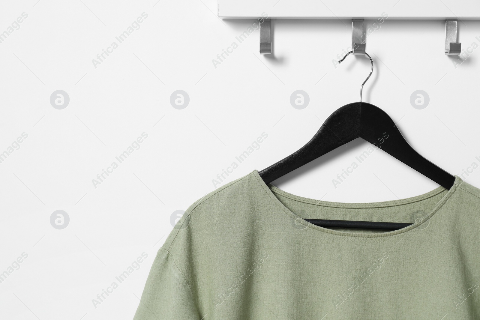 Photo of Hanger with olive t-shirt on white wall, space for text