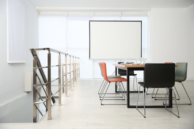 Photo of Modern meeting room interior with large table and projection screen