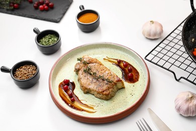 Beautiful composition with plate of delicious meat on white table in studio. Food stylist