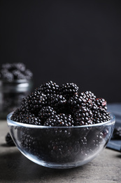 Delicious fresh ripe blackberries in glass bowl on grey table. Space for text