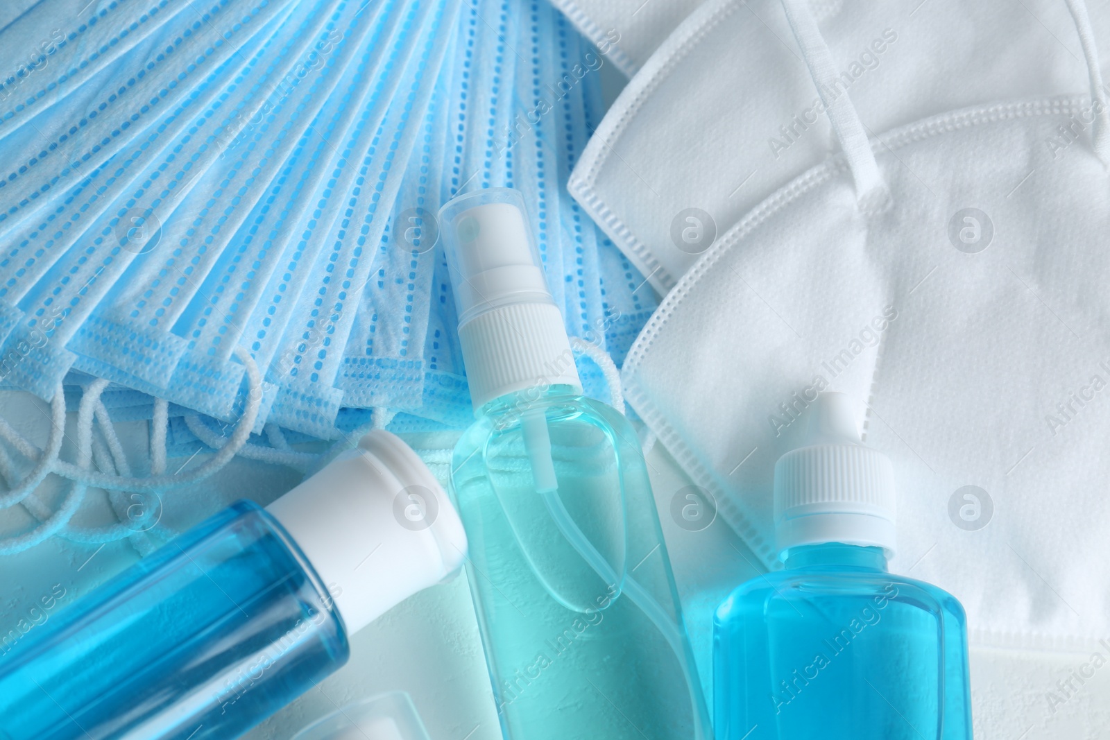 Photo of Hand sanitizers and respiratory masks on white table. Protective essentials during COVID-19 pandemic