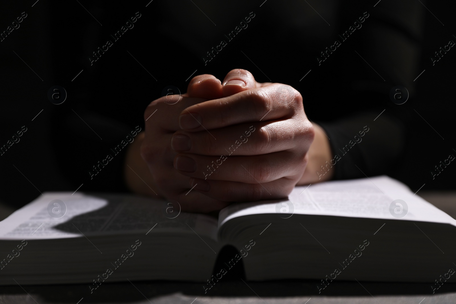 Photo of Religion. Christian woman praying over Bible at table, closeup