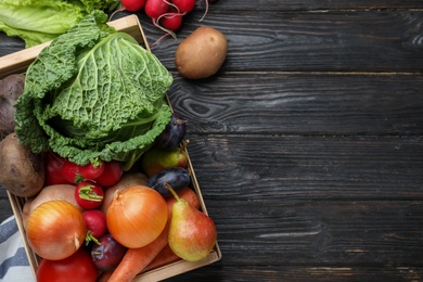 Crate full of harvested vegetables and fruits on black wooden table, flat lay. Space for text