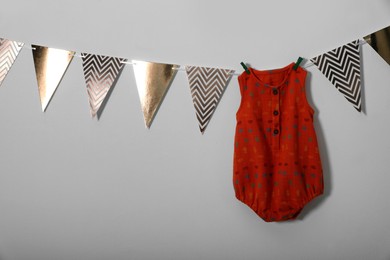 Photo of Baby bodysuit and bunting flags on light grey background