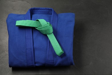 Photo of Green karate belt and blue kimono on gray background, top view. Space for text